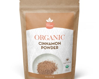 May include: A brown paper bag with a white label that says "ORGANIC CINNAMON POWDER" and features a picture of cinnamon powder in a white bowl. The label also includes the text "Vegan Friendly" and "USDA Organic". The bag is 8 ounces (227 grams).