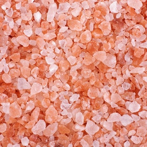 Pu&ograve; includere: Primo piano di cristalli di sale rosa dell'Himalaya. Il sale &egrave; di colore rosa chiaro e ha una consistenza ruvida.
