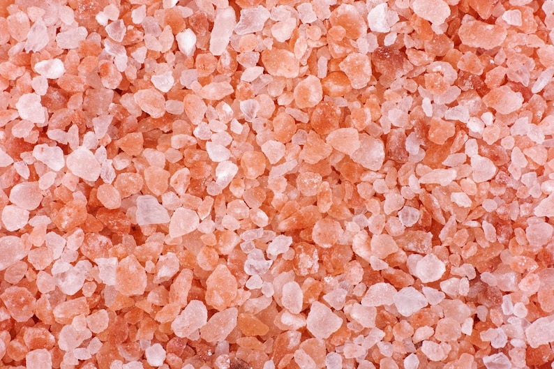 Pu&ograve; includere: Primo piano di cristalli di sale rosa dell'Himalaya. Il sale &egrave; di colore rosa chiaro e ha una consistenza ruvida.