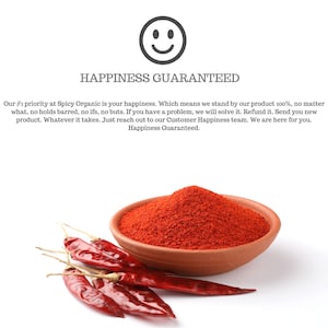 Op de afbeelding: Een kom met rode chilipeperpoeder met rode pepers op een wit oppervlak. De tekst "Happiness Guaranteed" staat in zwarte tekst op een witte achtergrond.