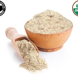 May include: A wooden bowl filled with light brown organic flour, with a wooden scoop beside it, spilling some flour onto a white surface. The bowl and scoop are both made of natural wood. The USDA Organic seal is visible in the upper right corner of the image.