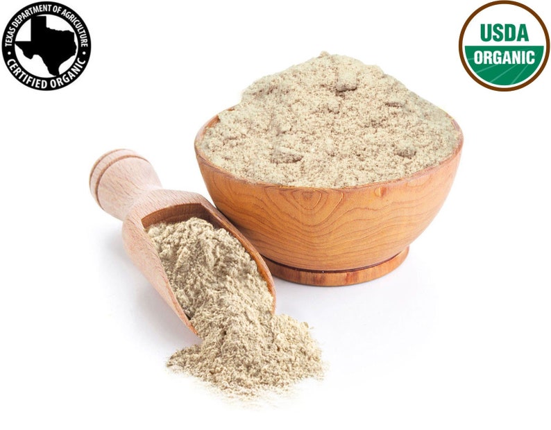 May include: A wooden bowl filled with light brown organic flour, with a wooden scoop beside it, spilling some flour onto a white surface. The bowl and scoop are both made of natural wood. The USDA Organic seal is visible in the upper right corner of the image.