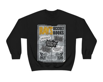 May include: Black sweatshirt with a vintage-style advertisement for "Ray's Occult Books." The ad features a variety of items for sale, including crystals, ritual herbs, incense and oils, and spiritual tomes. The ad also includes the store's address and hours of operation.