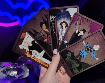 May include: A spread of tarot cards featuring illustrations of people and symbols. The cards are fanned out in a hand, revealing the cards "The Fool", "II", "III", and "The Empress".