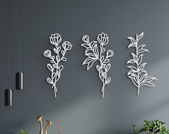 May include: Three white metal wall decor pieces featuring stylised floral designs. The pieces are arranged in a row on a grey wall.