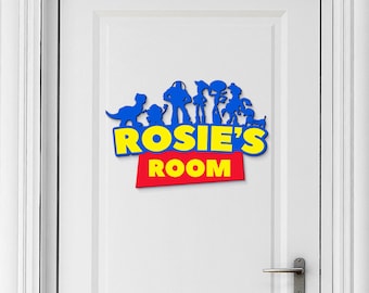 May include: A blue and yellow wooden door sign with the text "ROSIE'S ROOM" in a red rectangle. The sign features a silhouette of characters from the Toy Story movie franchise.