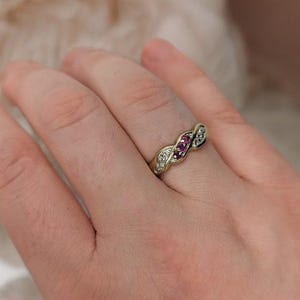 Peut inclure: Une bague en or avec un design de bande torsadée, comportant une rangée centrale de trois petites pierres précieuses roses rondes, flanquée de deux rangées de minuscules pierres blanches claires serties le long des courbes de l'anneau.