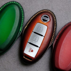 May include: Three leather key covers for a Nissan car key. The covers are green, orange, and red.