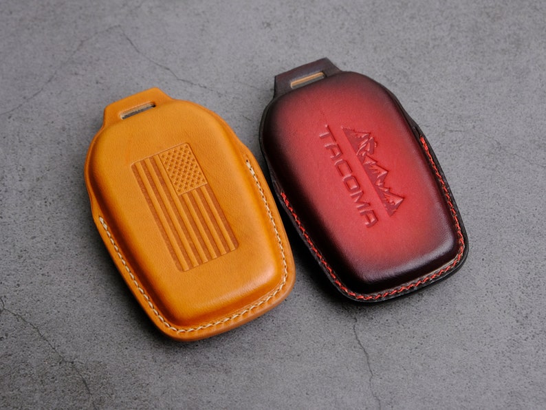 May include: Two leather key fobs, one tan with an American flag design and the other red with the word "TACOMA" and a mountain range design.