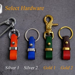 May include: Four different keychains with different colored leather straps and metal hardware. The hardware is either silver or gold. The keychains are labeled "Silver 1", "Silver 2", "Gold 1", and "Gold 2".