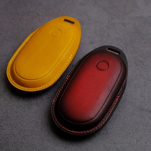 May include: Two leather keychains, one yellow and one red, with a stitched edge.