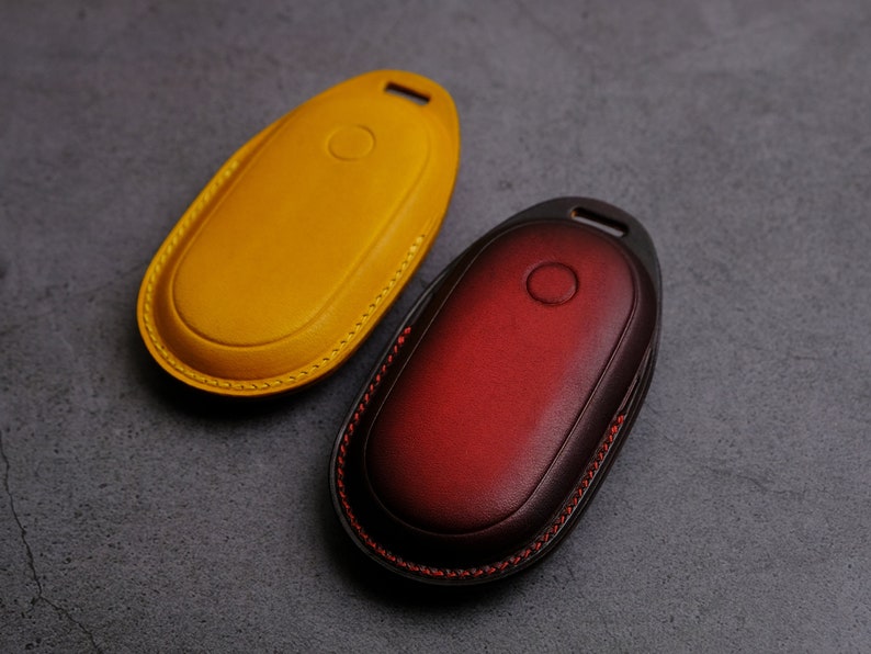 May include: Two leather keychains, one yellow and one red, with a stitched edge.
