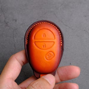 May include: Orange leather key fob with three buttons and the text "101 TOTO" on the bottom.