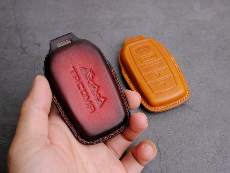 May include: Two leather key fobs, one red with the word "TACOMA" embossed and the other brown with multiple buttons.