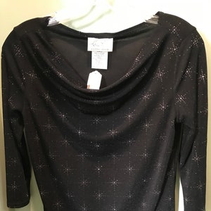 May include: Black long-sleeved top with a cowl neck and a silver star pattern. The tag reads "Lisa Collection".
