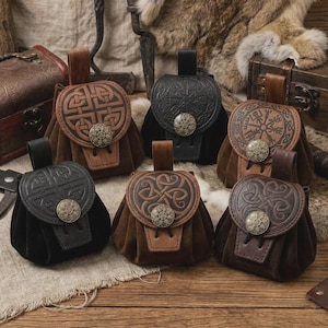 May include: A selection of handcrafted leather pouches in shades of brown and black. Each pouch features embossed Celtic knot designs, a flap closure, and a decorative metal button. The pouches are displayed on a wooden surface.