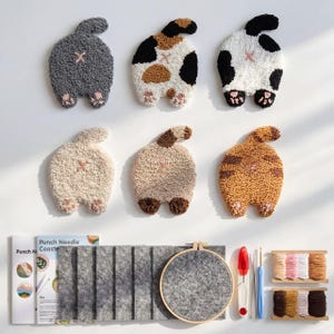 Può includere: Un set di sei sottobicchieri a forma di sedere di gatto in vari colori e motivi. I sottobicchieri sono realizzati con un tessuto strutturato e ad anello. È incluso anche un kit per l'artigianato con filo, un telaio e aghi.