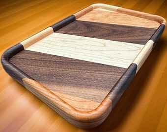 May include: A wooden serving tray with a rounded edge and a striped design in shades of brown, beige, and light brown.