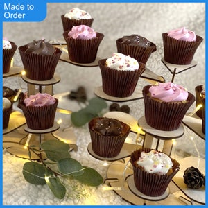 May include: A three-tier wooden cupcake stand, decorated with cupcakes in a variety of colours, including pink, white and brown. The stand is made of wood and has a natural finish. The cupcakes are topped with sprinkles and frosting. The stand is ideal for displaying cupcakes at a party or event.
