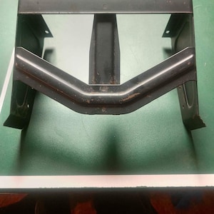 May include: A black metal frame with a curved top and two vertical supports. The frame is slightly rusted and has a worn appearance.