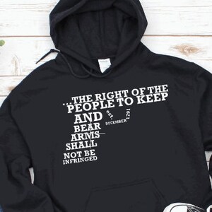 May include: Black hooded sweatshirt with white text that reads "...THE RIGHT OF THE PEOPLE TO KEEP AND BEAR ARMS SHALL NOT BE INFRINGED est. DECEMBER 1791"