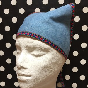 May include: A blue denim hat with a red and blue trim. The hat has a pointed top and a tie.