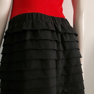May include: Black tiered skirt with a ruffled hem. The skirt is made of a soft, stretchy fabric and has a comfortable elastic waistband.