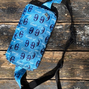 Sac banane unisexe bleu clair à rabat taille ceinture CONTE OF FLORENCE Logo bleu foncé et blanc imprimé plusieurs poches de rangement