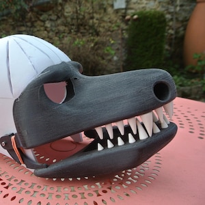 Könnte beinhalten: Ein weißer Schaumkopf mit einem daran befestigten schwarzen und weißen Dinosaurierkopf. Der Dinosaurierkopf hat einen großen Mund mit weißen Zähnen.