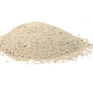 May include: A pile of light beige clay powder on a white background.