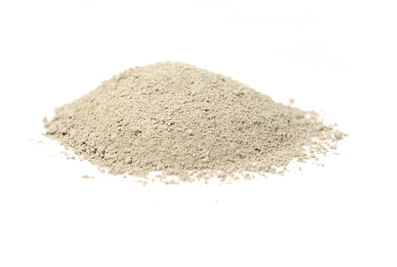 May include: A pile of light beige clay powder on a white background.