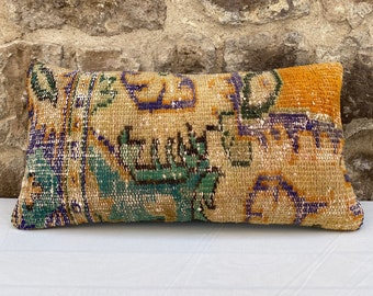 Può includere: Cuscino decorativo rettangolare dall'aspetto vintage e usurato. Il cuscino presenta uno sfondo beige con un motivo geometrico colorato nelle tonalità dell'arancione, del verde, del blu e del viola. Il cuscino è probabilmente realizzato in materiale tessuto.