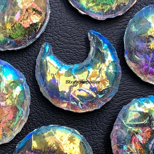May include: A collection of iridescent glass crescent moon shapes. The glass is clear with a rainbow sheen. The moons are various sizes and are arranged on a black surface.  StoneSupplier is printed on one of the moons.