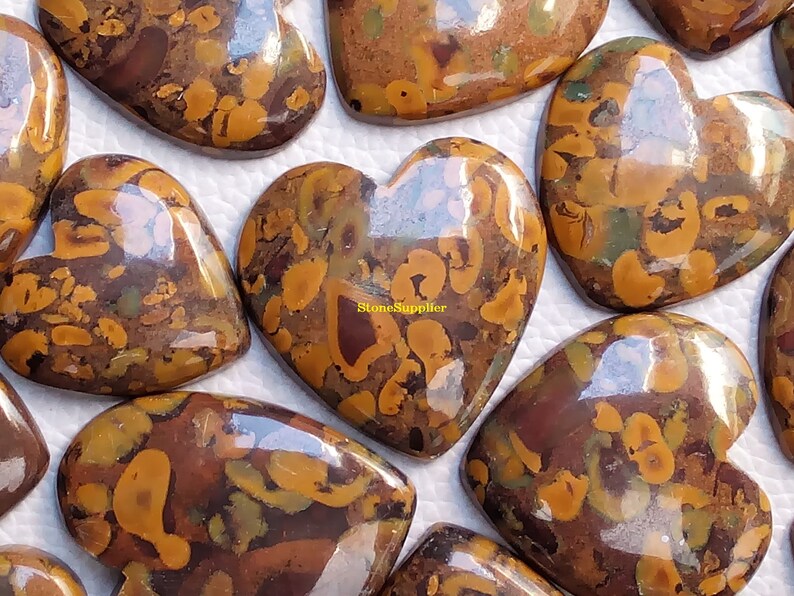 May include: A collection of polished heart-shaped stones with a brown, yellow, and green marbled pattern. The stones are smooth and shiny, and they have a unique and beautiful appearance.