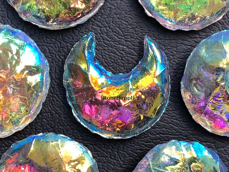 May include: A collection of iridescent glass moon and full moon shapes. The glass is clear with a rainbow sheen.