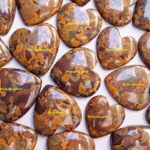 May include: A collection of 14 heart-shaped polished stones with a brown, orange, and green marbled pattern. The stones are approximately 5 cm in length and 4 cm in width.