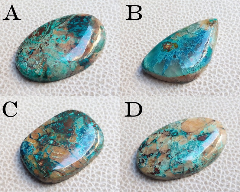 K&ouml;nnte beinhalten: Vier ovale T&uuml;rkis-Cabochons mit braunen und kupferfarbenen Einschl&uuml;ssen. Die Cabochons sind mit A, B, C und D gekennzeichnet.