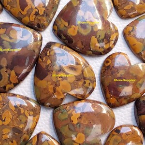 May include: A collection of heart-shaped, polished, brown, yellow, and green jasper cabochons. The cabochons have a mottled, marbled pattern.