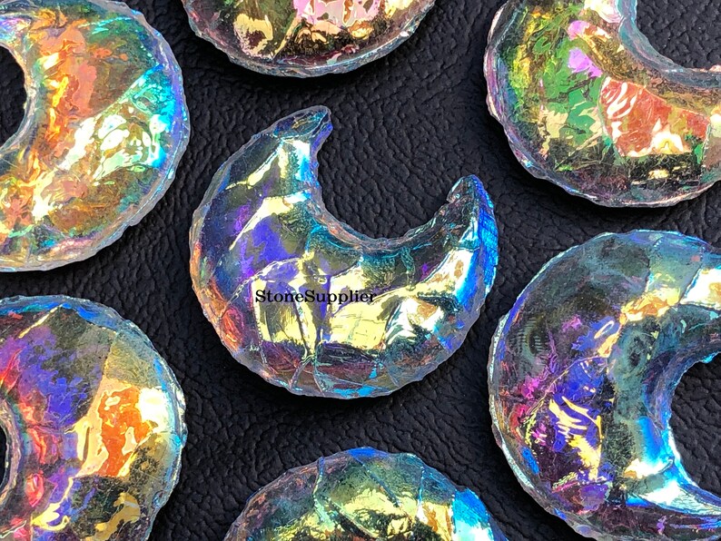 May include: A collection of iridescent glass crescent moon shapes. The glass is clear with a rainbow sheen.