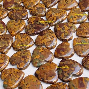 May include: A collection of heart-shaped, polished, brown, yellow, and green jasper stones. The stones have a mottled, marbled appearance.