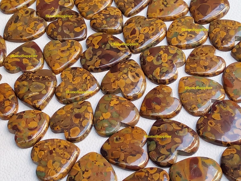 May include: A collection of heart-shaped, polished, brown, yellow, and green jasper stones. The stones have a mottled, marbled appearance.