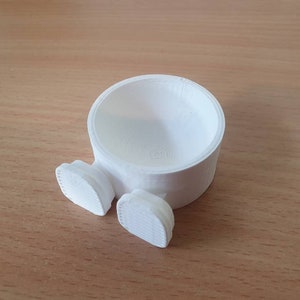 Op de afbeelding: Een witte keramische plantenpot met twee kleine voetjes. De pot is rond en heeft een gladde, witte afwerking.