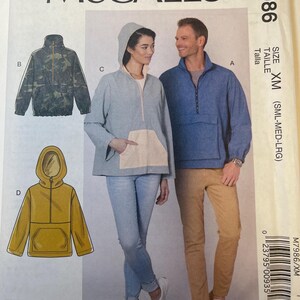 May include: McCall's sewing pattern M7986. The pattern features illustrations of various jacket styles, including a camouflage print jacket, a hooded jacket with a light blue body and a beige pocket, and a mustard yellow hooded jacket. The size is XM (SML-MED-LRG).