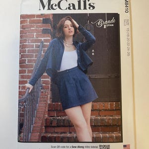 May include: McCall's sewing pattern M8410 featuring a woman wearing a denim jacket and skirt. The pattern includes sizes Y5 (18-20-22-24-26). The cover has the text "Brandi Joan" and a QR code for a video tutorial. Designed and printed in the USA.