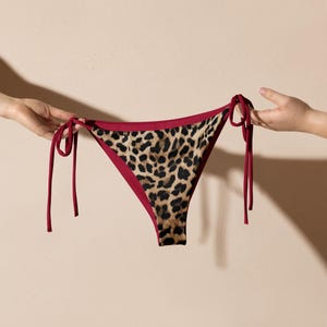 May include: Leopard print bikini bottom with red trim and ties.