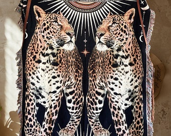 May include: Black and white tapestry featuring two leopards with a starburst design in the center. The leopards are facing each other and have a black and white spotted pattern.