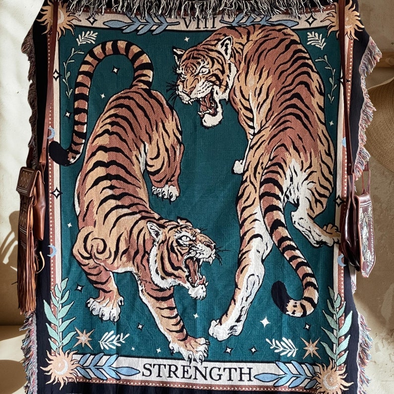 May include: A tapestry featuring two tigers with a green background. The tapestry has a border with gold and white accents. The text "VIII STRENGTH" is printed at the bottom of the tapestry.
