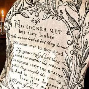 May include: A black and white print on a cream-colored fabric with a floral design. The print features a poem from 1598 that reads: "NO SOONER MET but they looked No sooner looked but they loved No sooner loved but they sighed No sooner sighed but they asked one another the reason NO SOONER KNEW THE REASON But they sought the remedy And in these degrees have they made A pair of stairs"