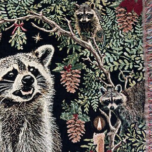 Raccoon woven tapestry blanket with candles, pinecones, winter greenery, mistletoe and holly berries.