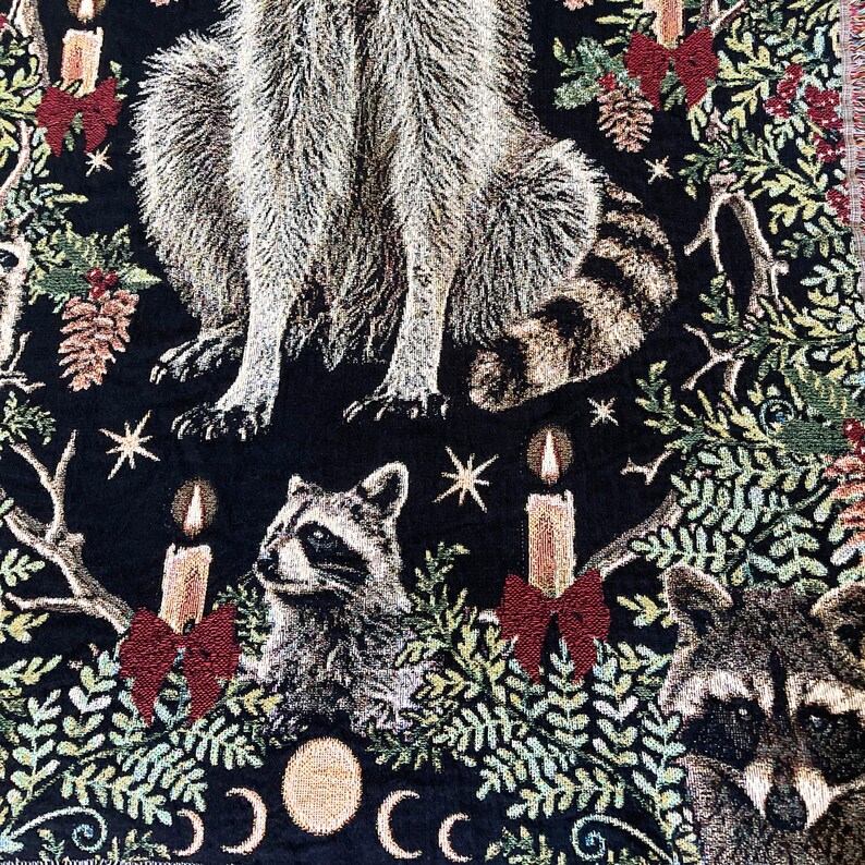Raccoon woven tapestry blanket. All cotton with a black background a large raccoon sits in the center of botanicals, christmas candles, red bows, pinecones, holly berries and several other cheeky raccoons. Adorable christmas gift for raccoon lovers.